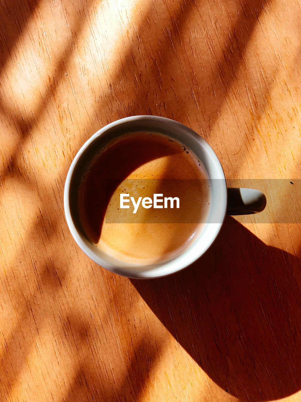 HIGH ANGLE VIEW OF COFFEE CUP ON WOODEN TABLE