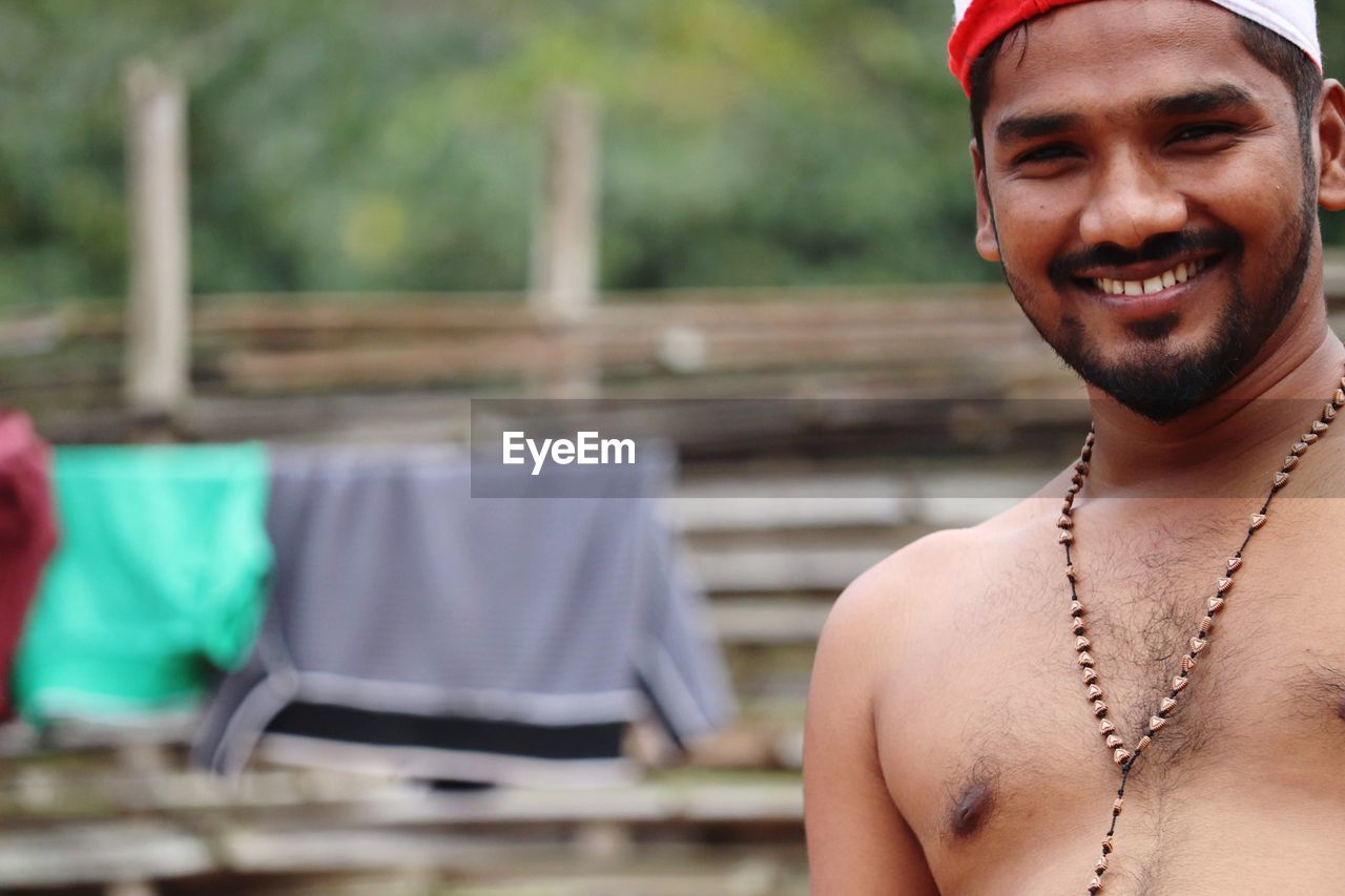 adult, portrait, smiling, happiness, men, one person, emotion, young adult, headshot, person, looking at camera, clothing, water, cheerful, beard, jewelry, facial hair, lifestyles, nature, barechested, smile, human face, day, outdoors, teeth, necklace, focus on foreground, summer, front view, hat