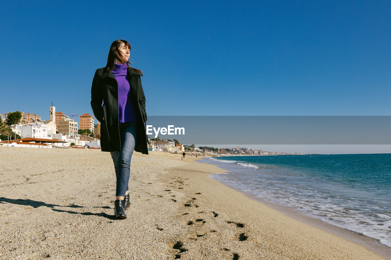 Mature woman walking on the beach on a sunny winter day