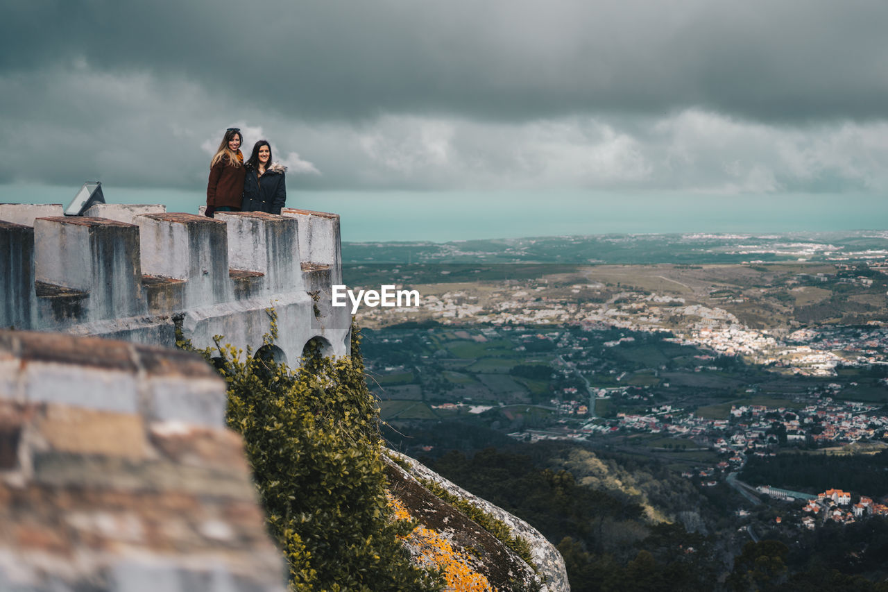 Friends standing on castle against cloudy sky