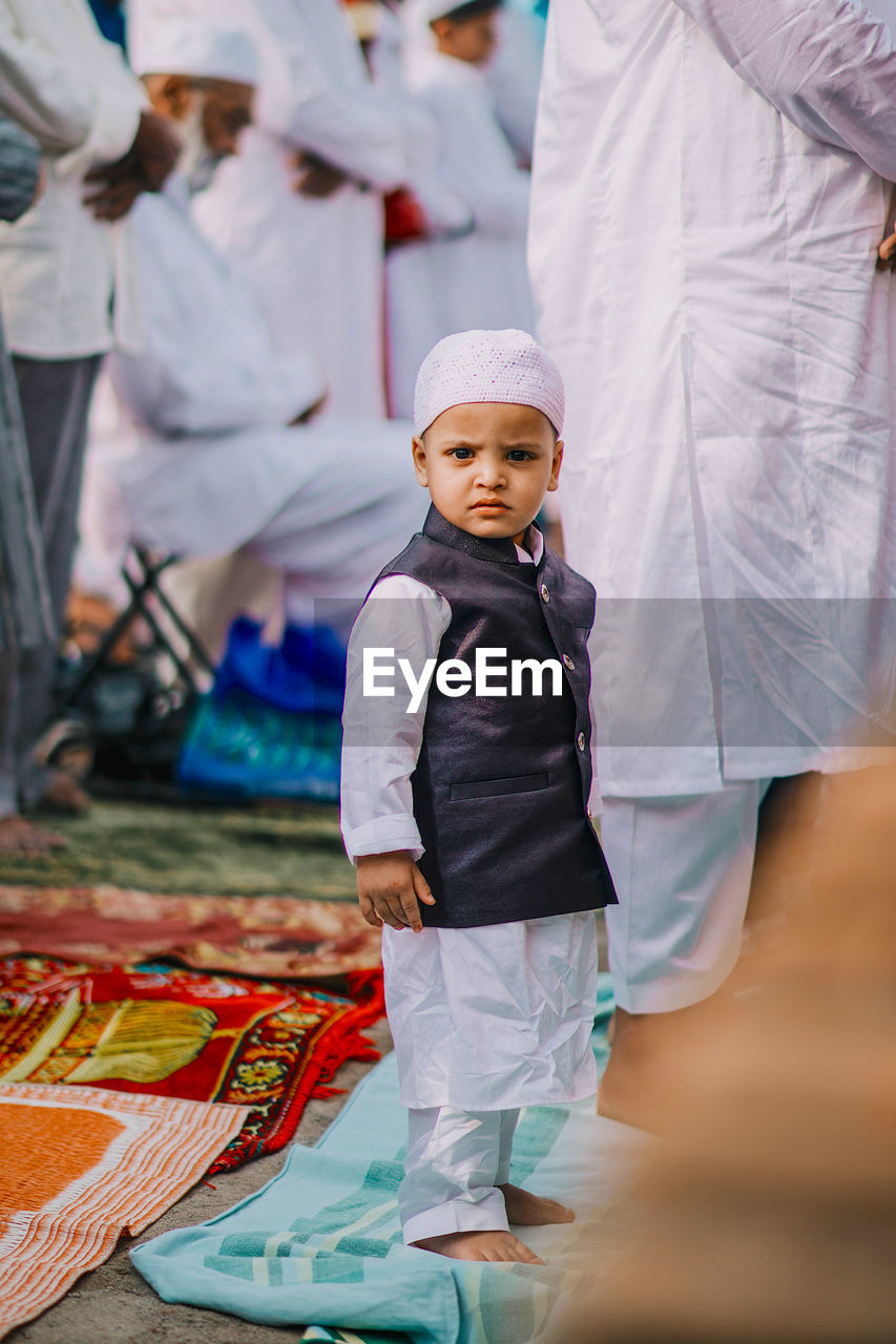Portrait of cute boy in traditional clothing standing on mat