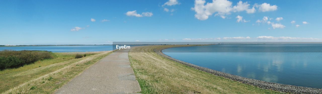 PANORAMIC VIEW OF ROAD BY SEA AGAINST BLUE SKY