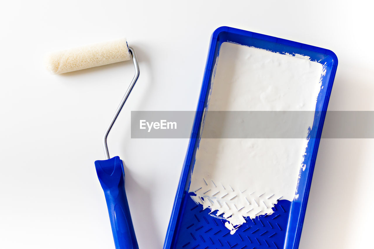 Paint roller and tray with white paint for interior renovation and decoration