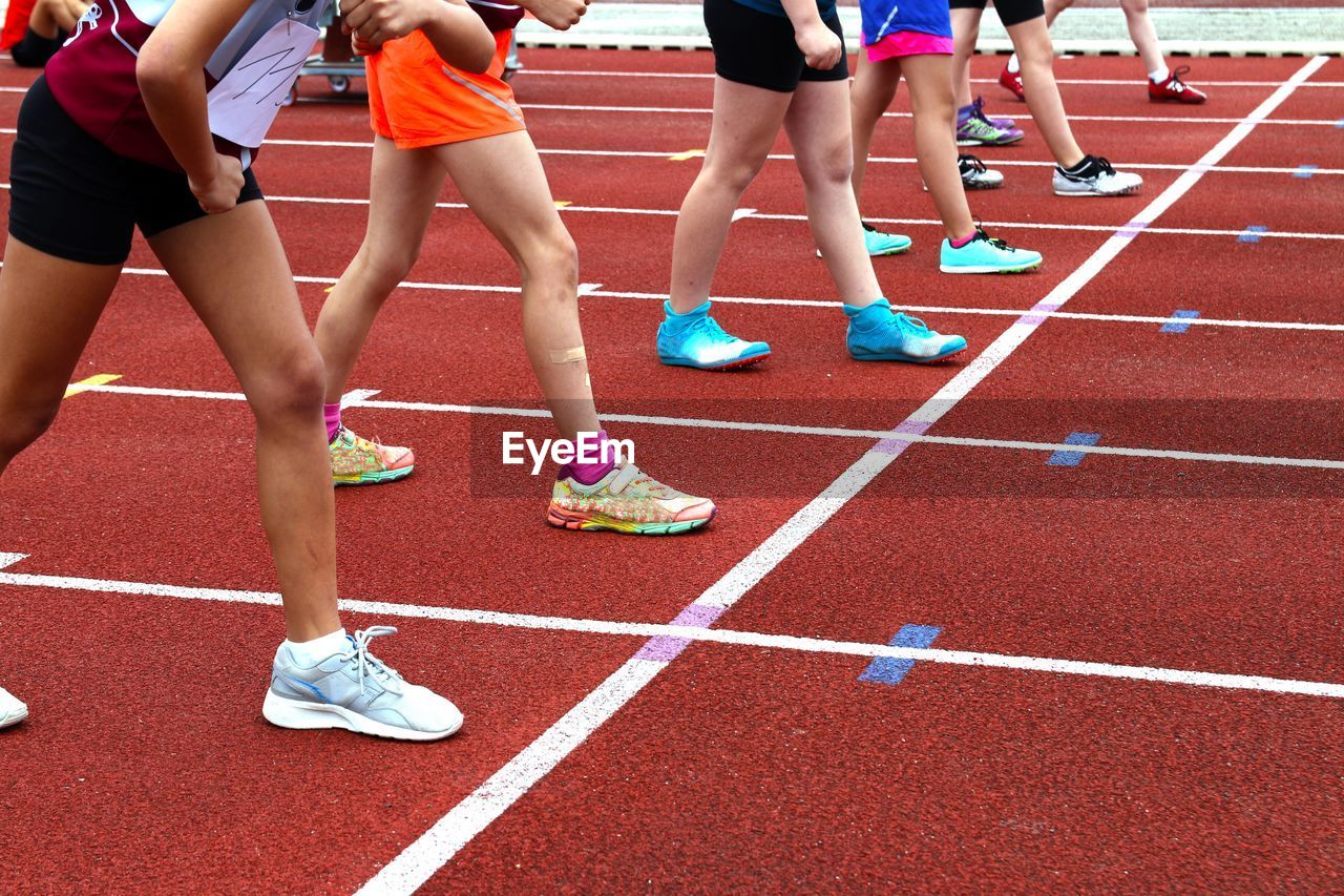 Low section of athletes standing on running track 