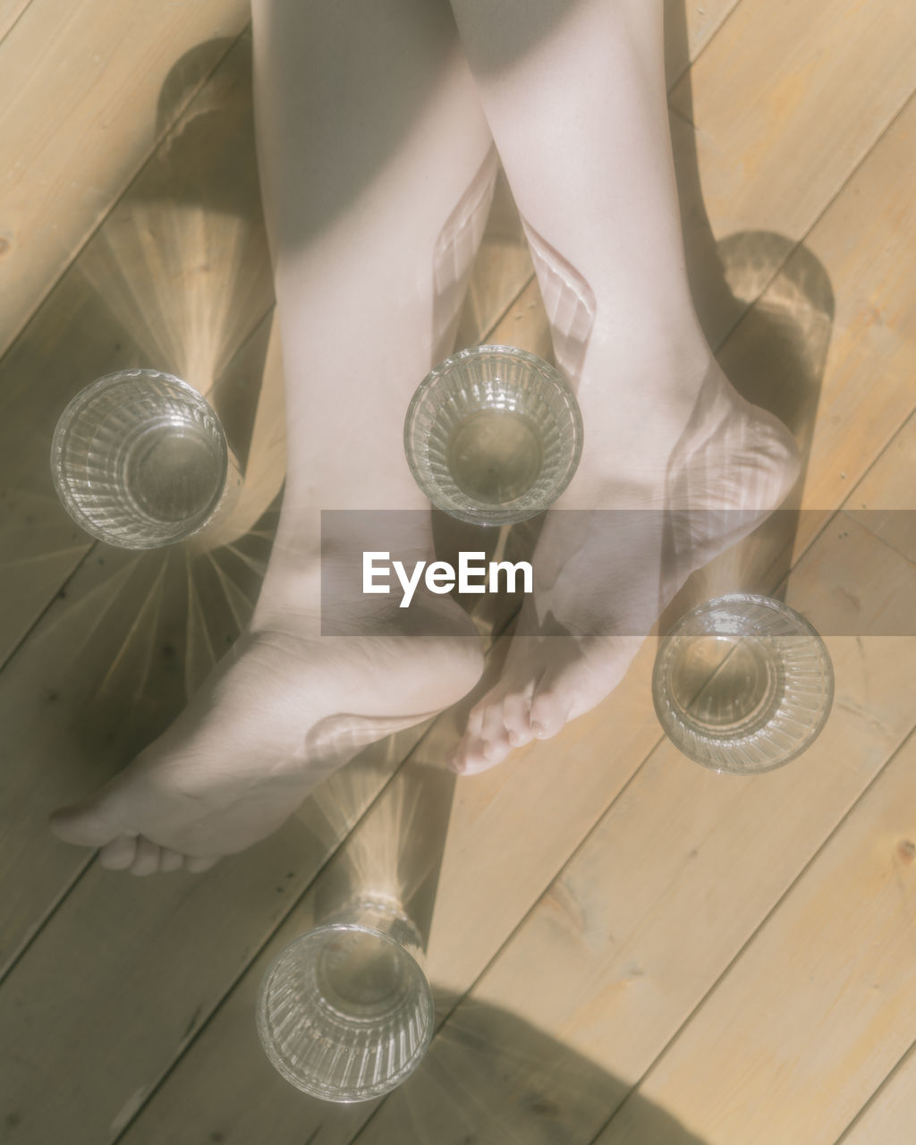 Low section of woman with glass on wooden floor