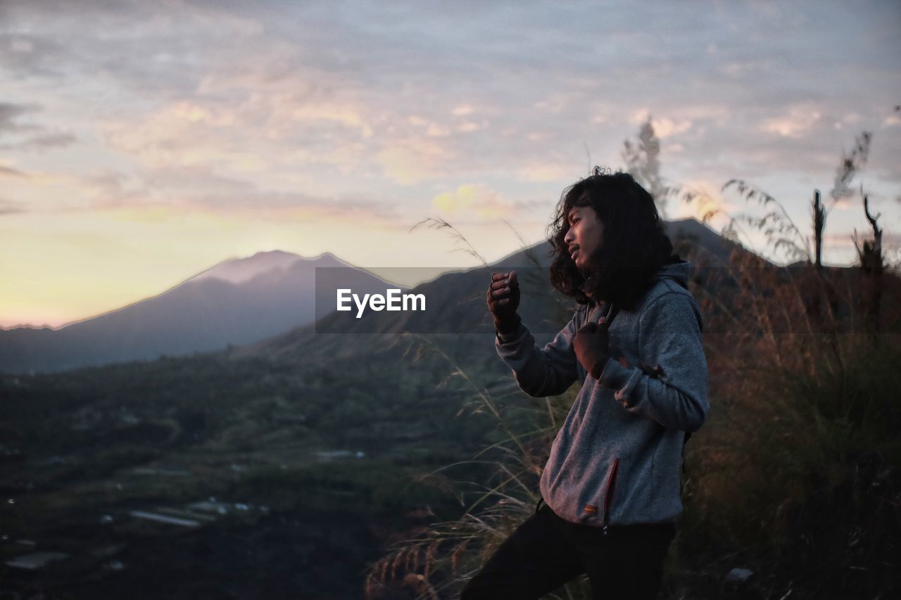 Man standing on mountain against sky during sunset