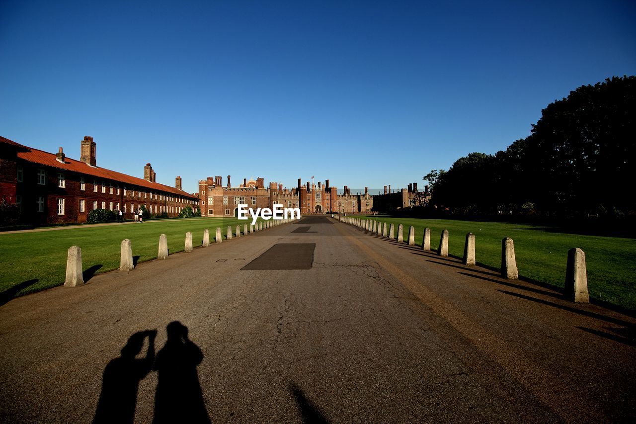 Shadow of people on road in front of hampton court palace