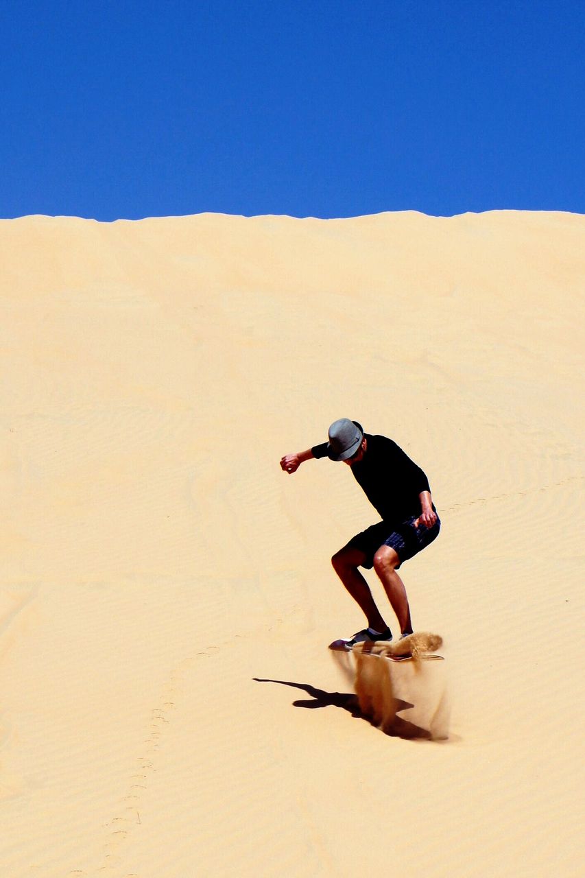 Full length of man sandboarding in desert