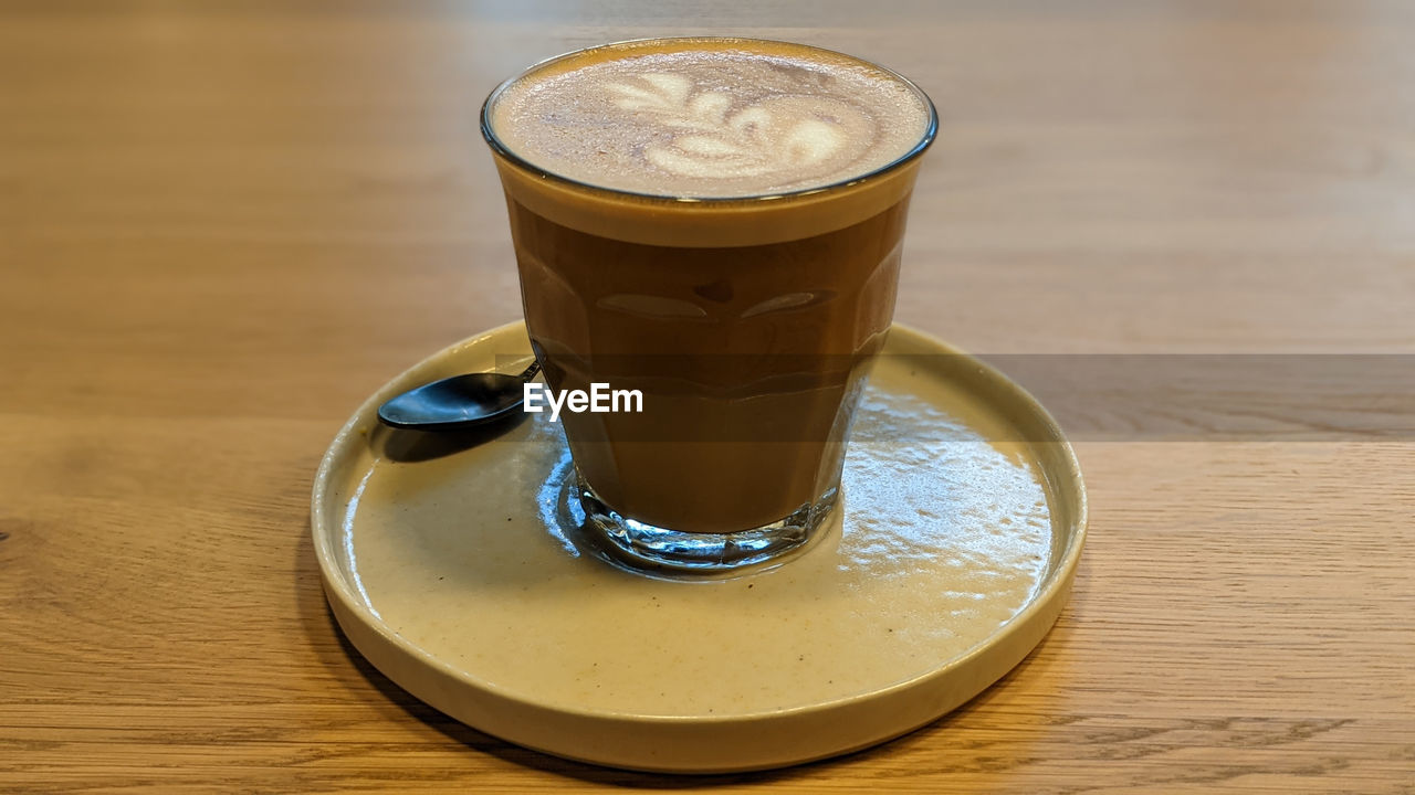 drink, food and drink, refreshment, table, coffee, latte, glass, drinking glass, household equipment, wood, saucer, cup, mug, still life, coffee milk, indoors, frothy drink, cortado, food, crockery, freshness, coffee cup, café au lait, hot drink, no people, cafe, close-up
