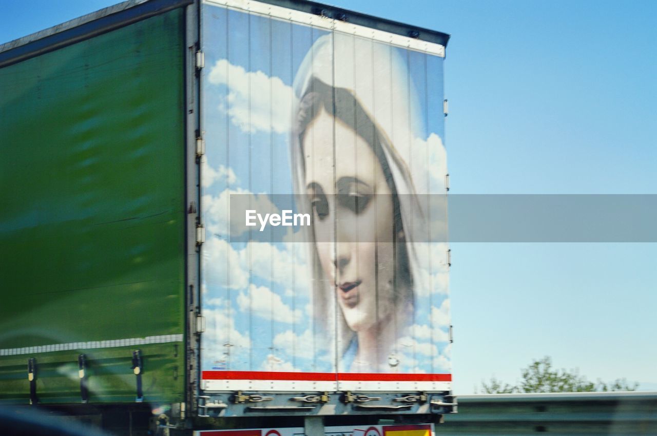 PORTRAIT OF YOUNG WOMAN AGAINST SKY SEEN THROUGH CAR