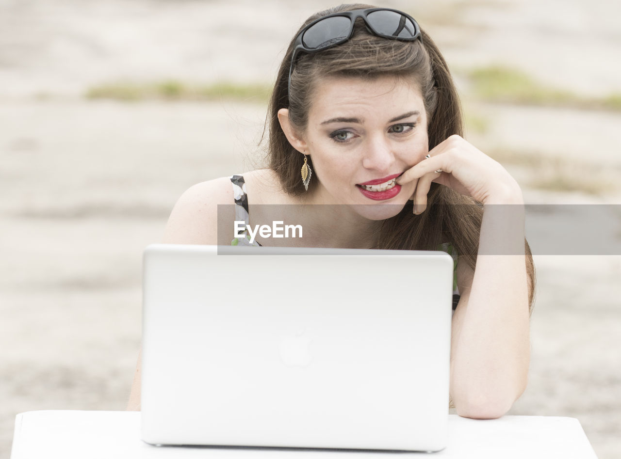 Close-up of young woman using laptop at beach
