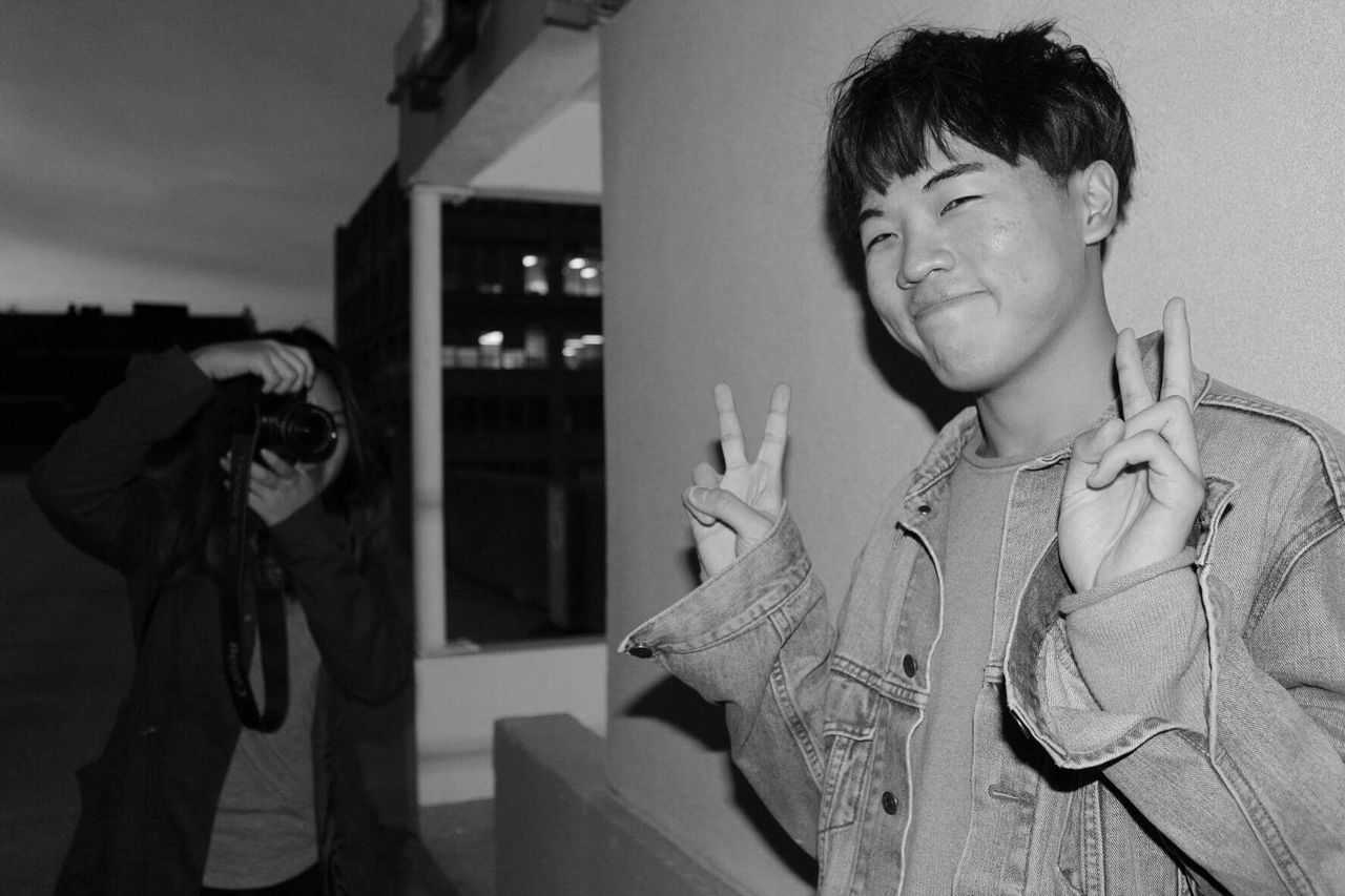 Woman photographing friend showing peace signs