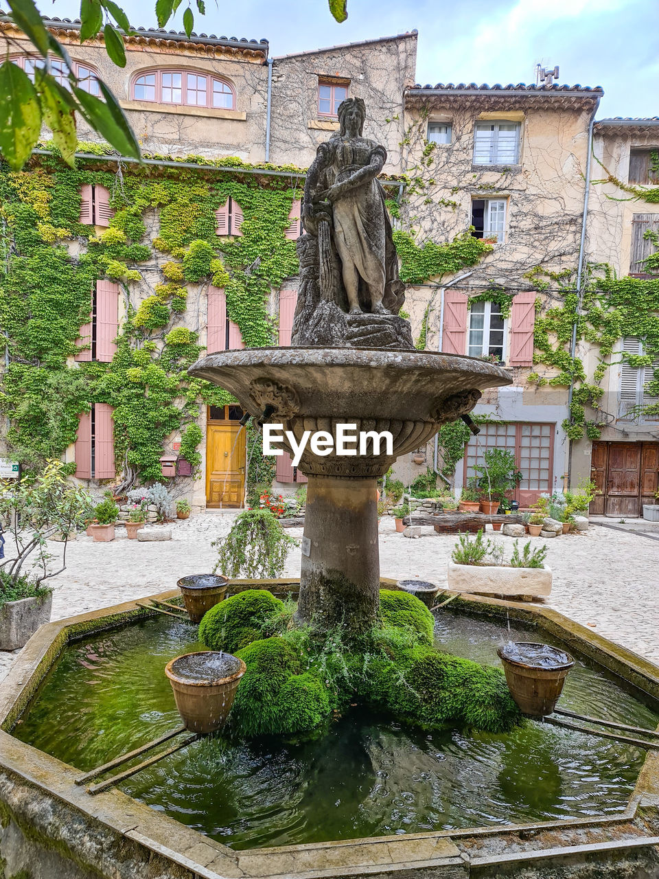STATUE BY FOUNTAIN AGAINST BUILDINGS