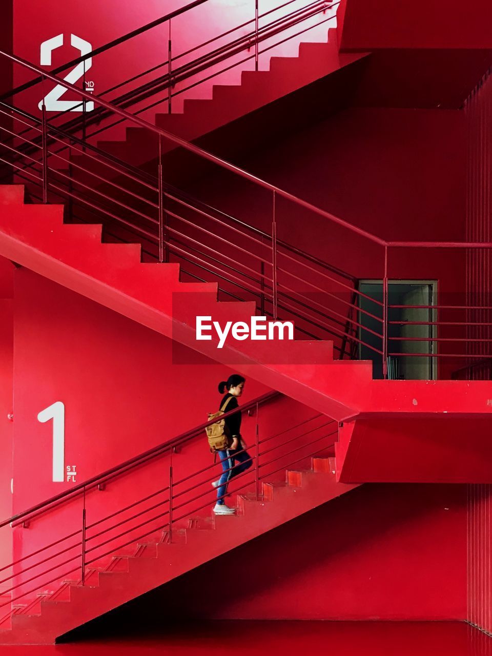 Woman walking on staircase of red building