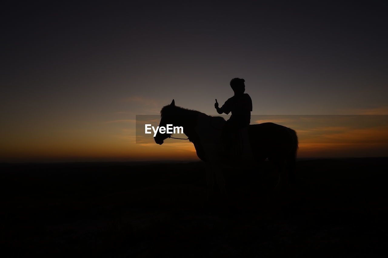 Silhouette man riding horse