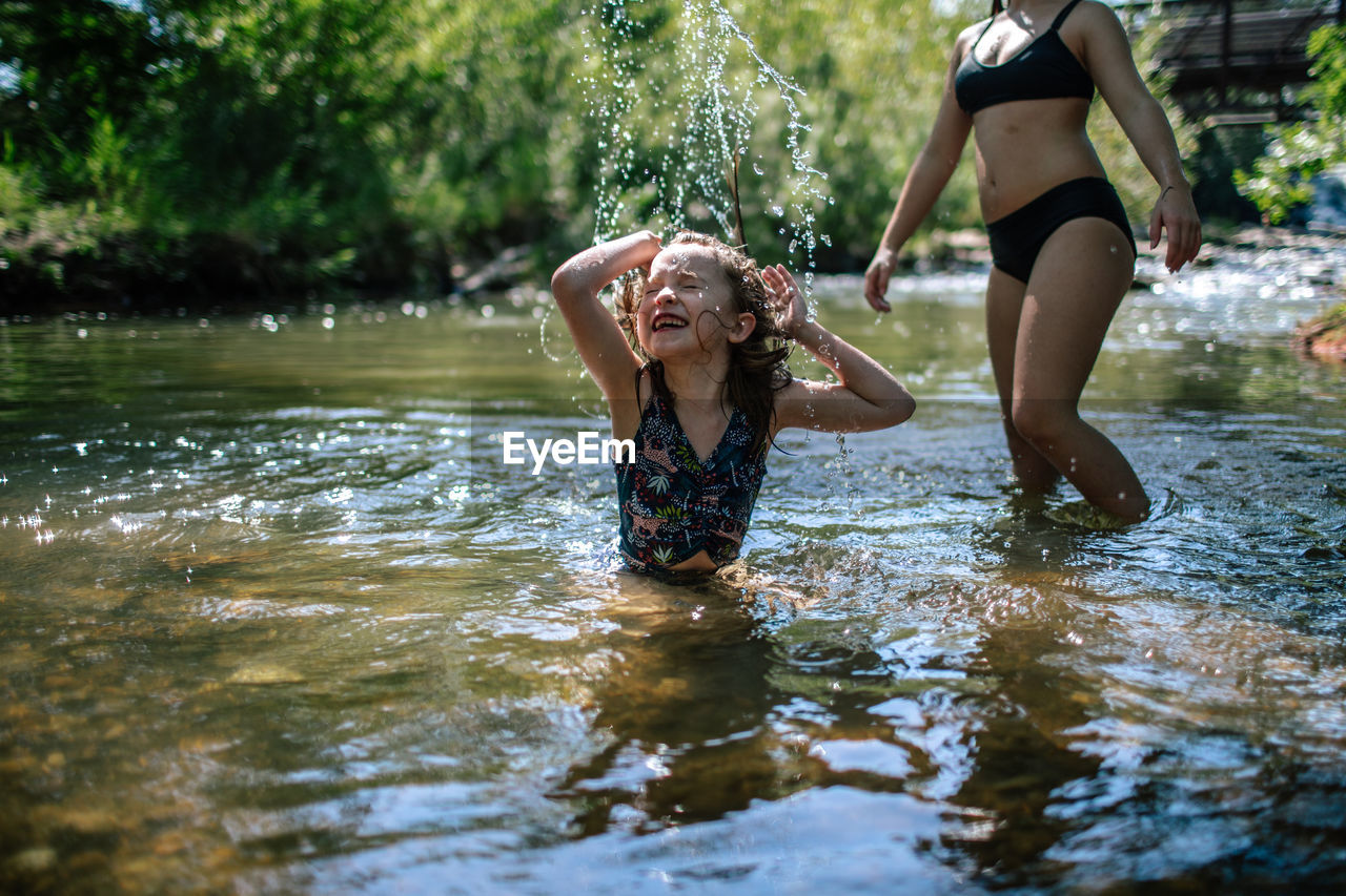 Happy young girl splashing in a creek on a warm day