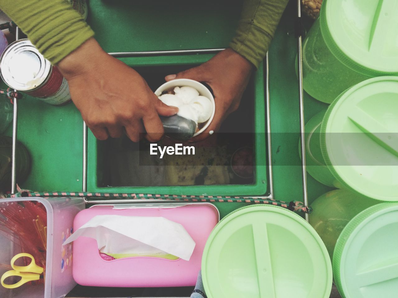Cropped image of vendor filling coconut ice cream scoops in cup at concession stand