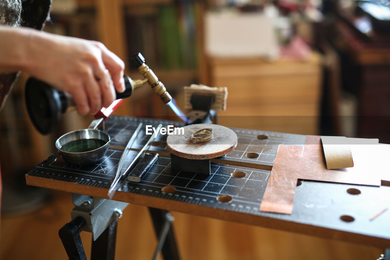 Home workshop girl master on a gas burner in a meta-liter scoop boils water with a copper plate, 