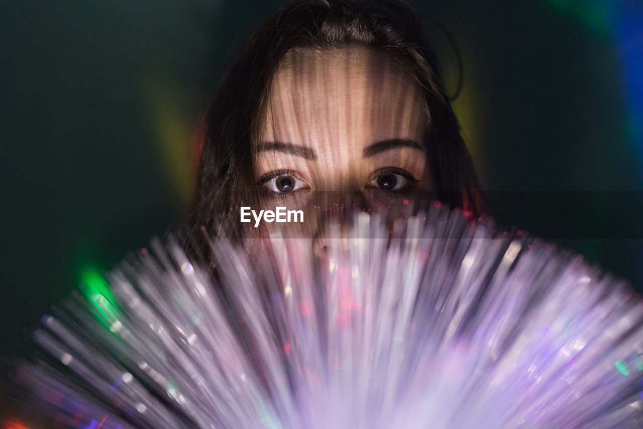 Close-up portrait of young man with illuminated fiber optics