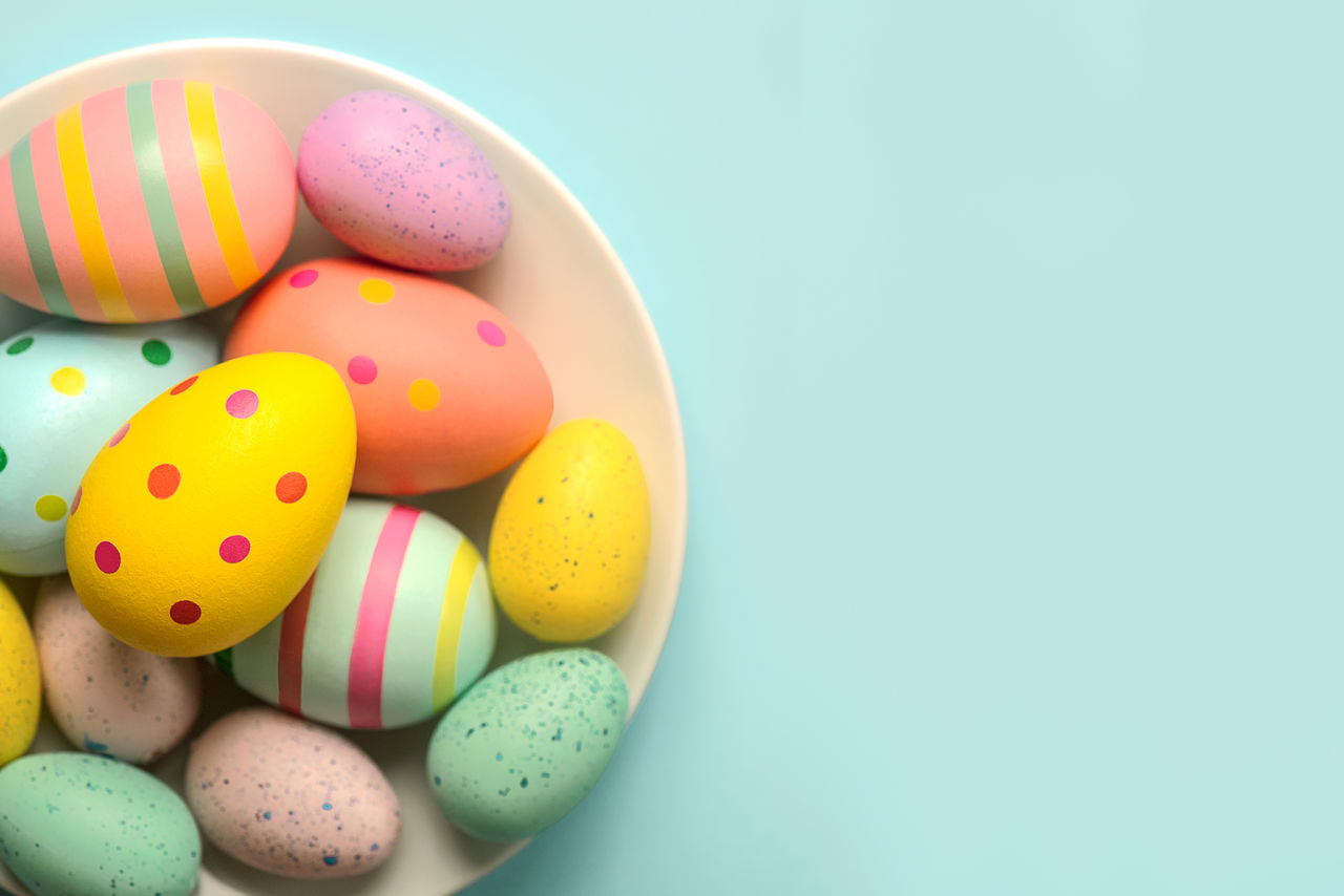 high angle view of multi colored easter eggs in bowl on blue background