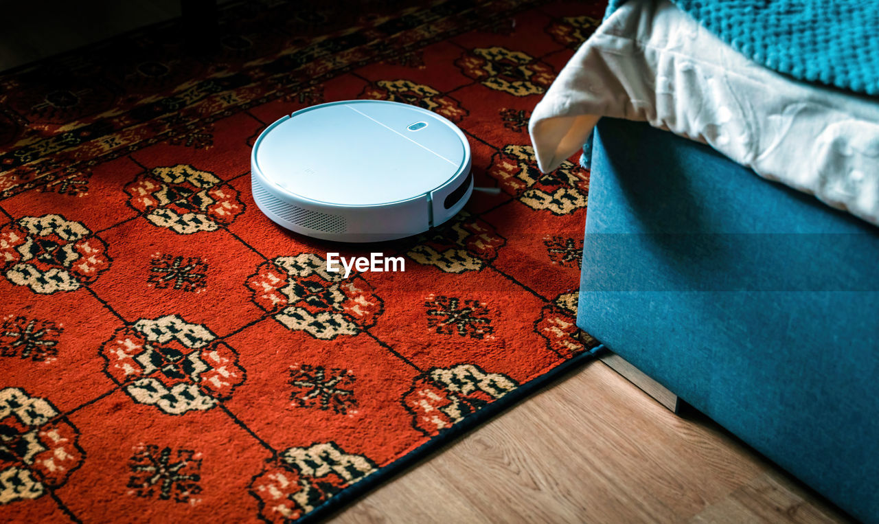 Robot vacuum cleaner and mop cleaning carpet in bed room floor. modern smart device housekeeping.