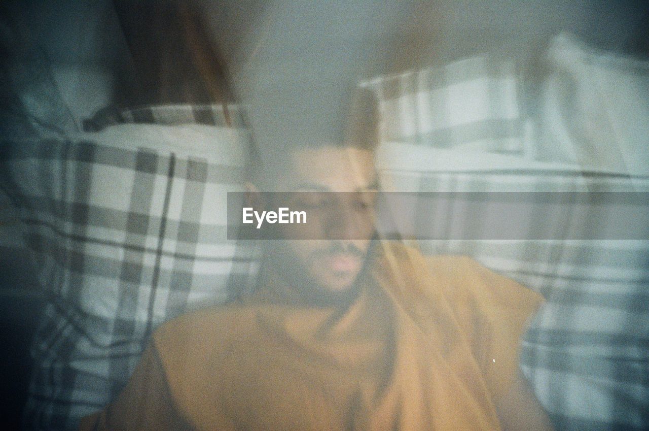 DIGITAL COMPOSITE IMAGE OF YOUNG MAN WITH CURTAIN