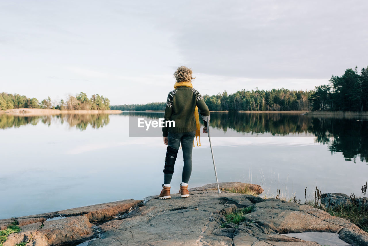 Injured woman stood at the waters edge looking at the beautiful view