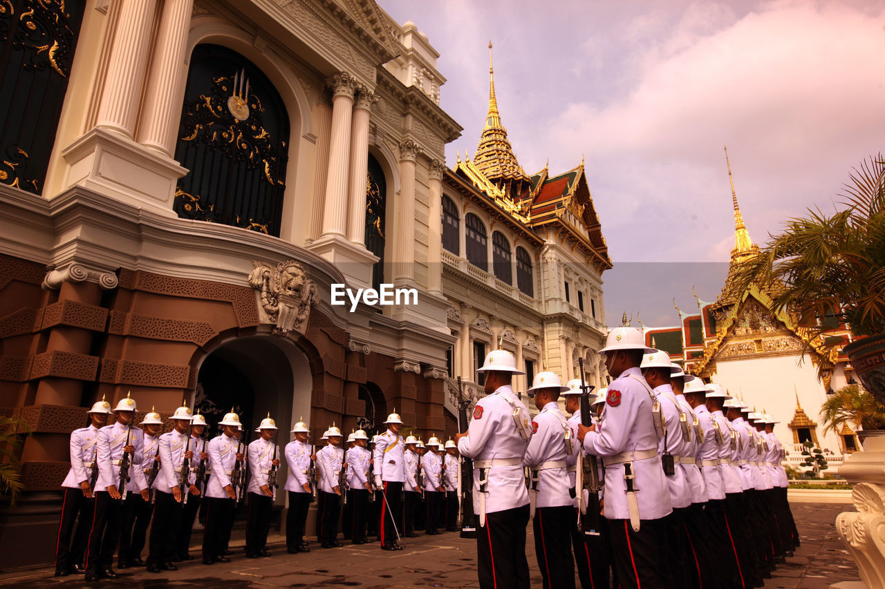 Military officers standing outside temple against sky