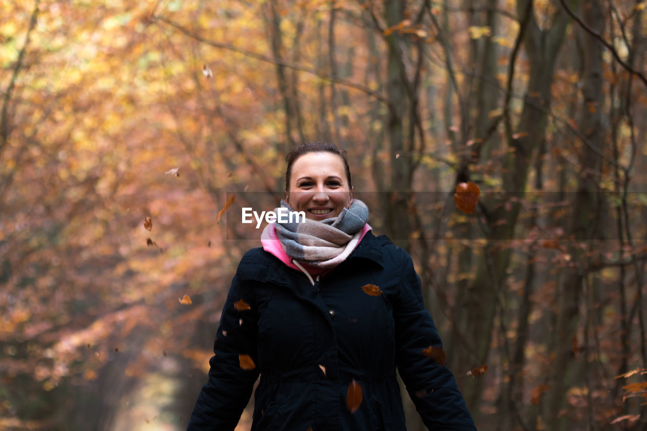 Portrait of smiling woman in forest during autumn