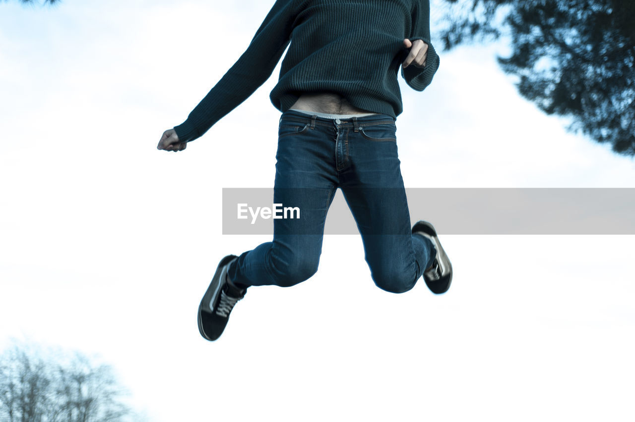 Low section of man jumping on snow