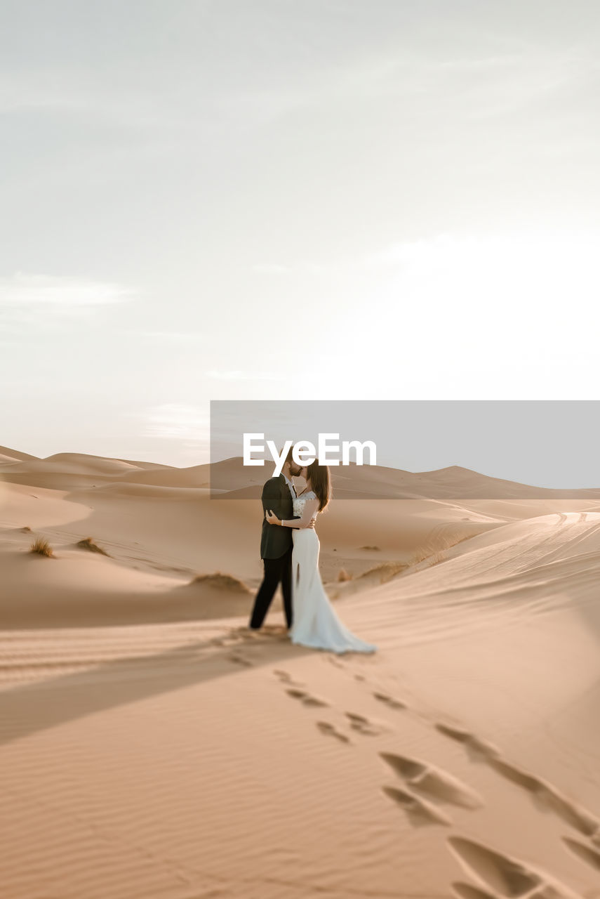Rear view of couple standing on sand dune