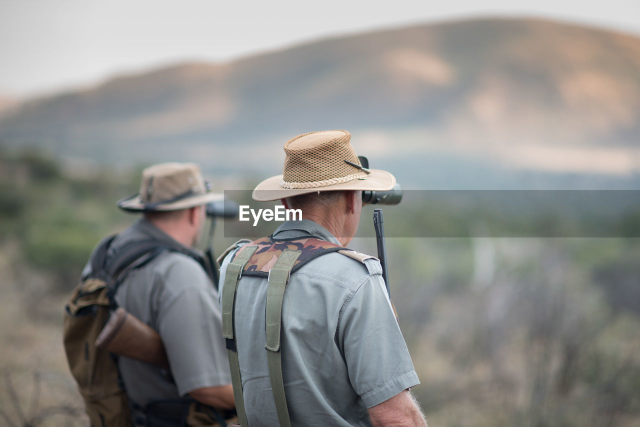 Side view of men looking through binoculars