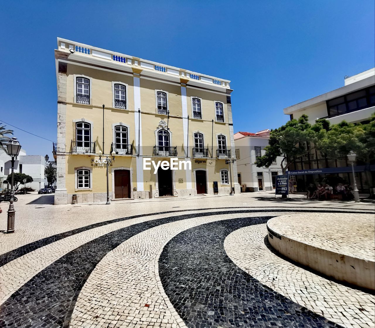 STREET BY BUILDINGS IN TOWN AGAINST CLEAR BLUE SKY