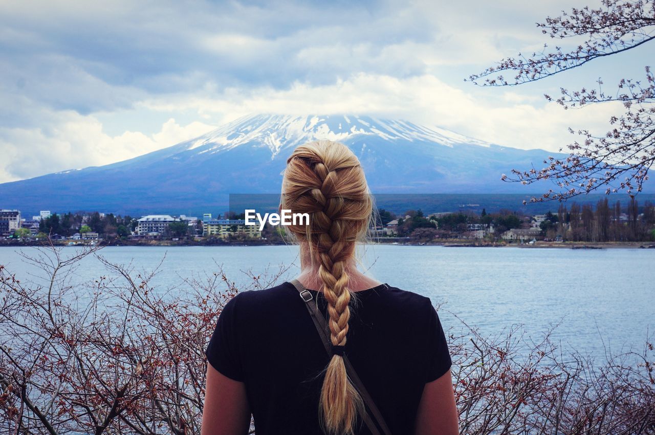 Rear view of woman with braided blond hair in front of mount fuji and river
