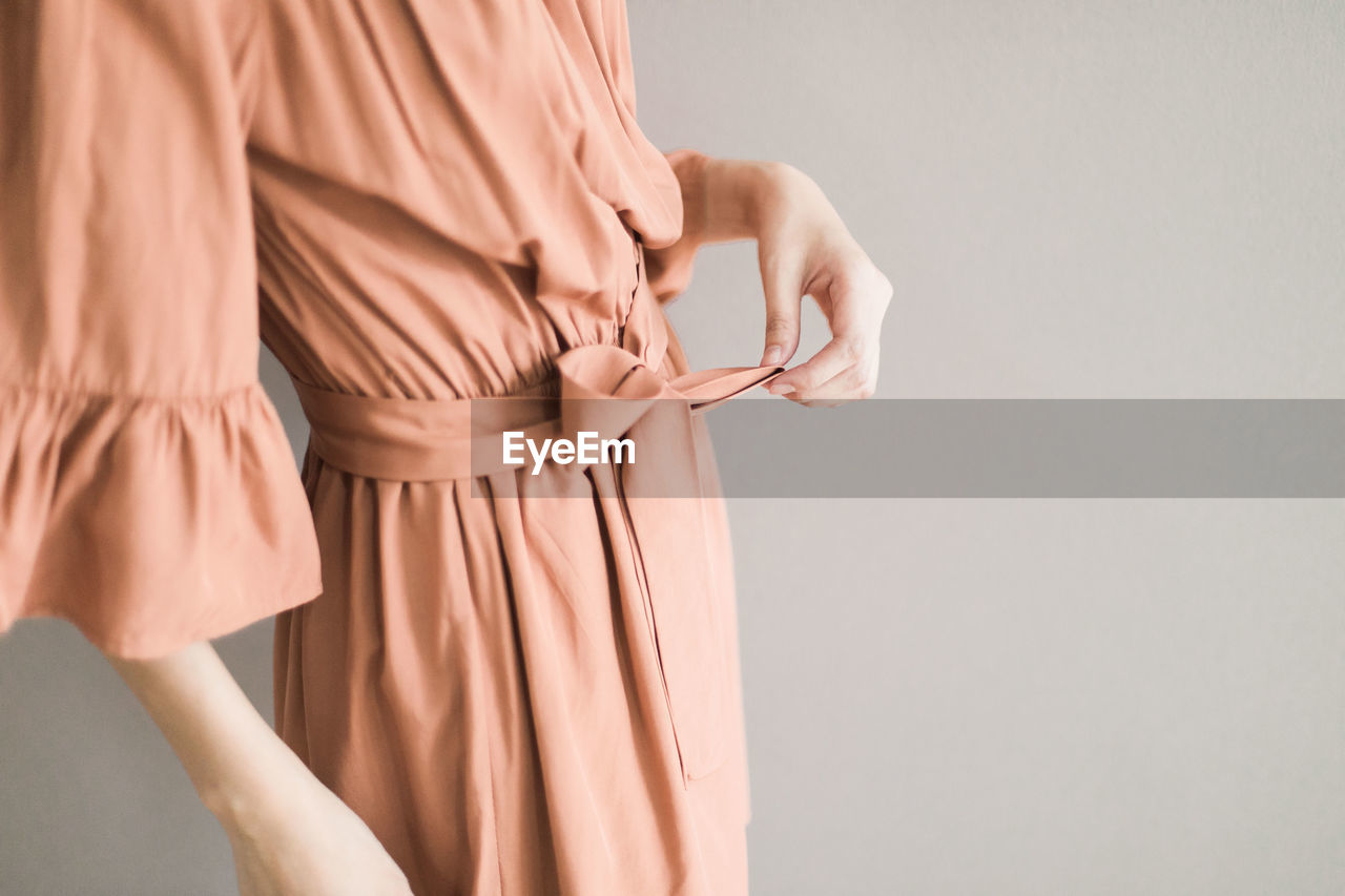 Midsection of woman standing against gray background