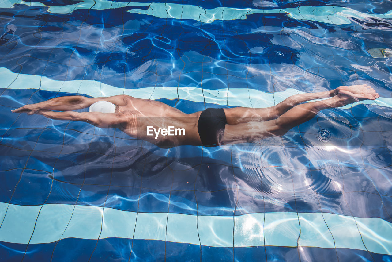 Low section of man swimming in pool
