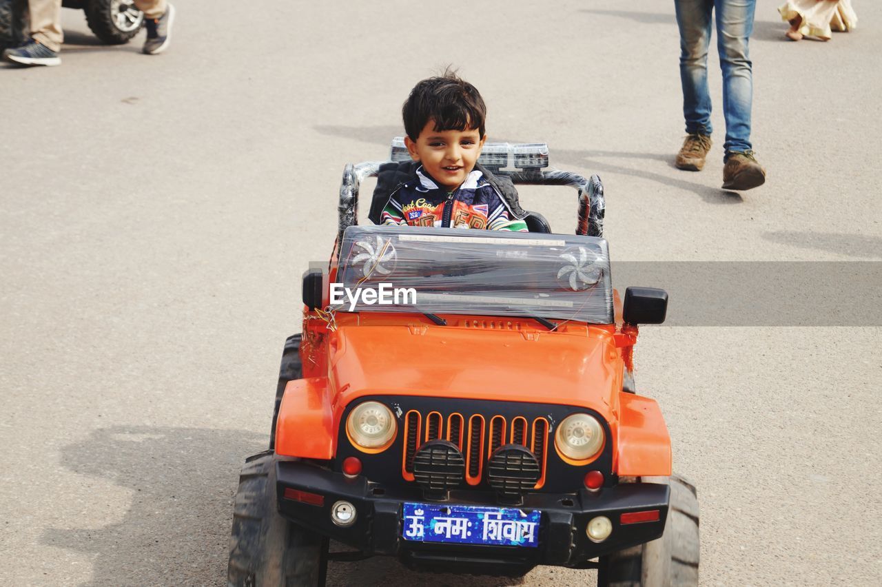 Portrait of boy sitting in toy car