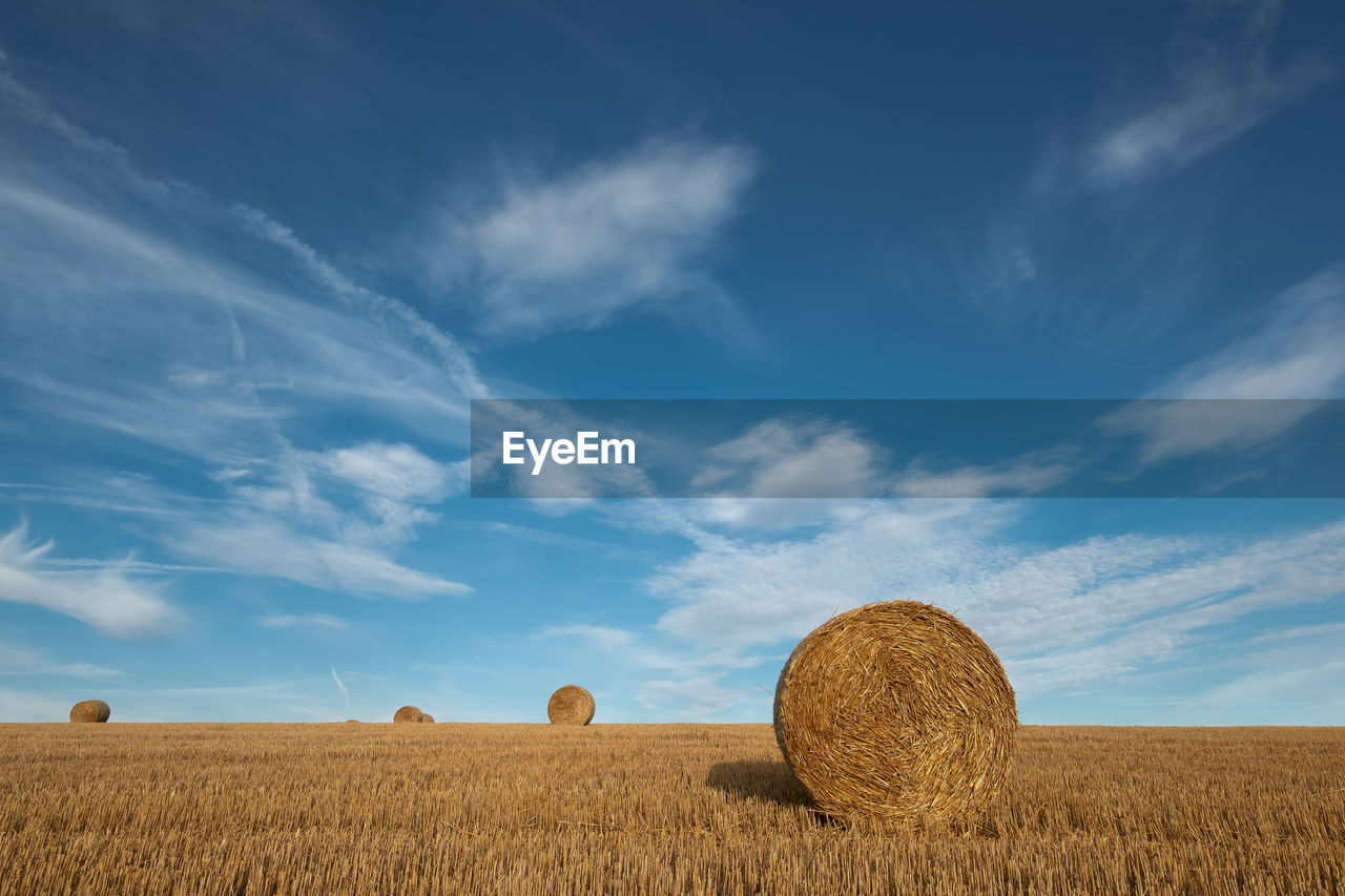 Hay bales on field against sky