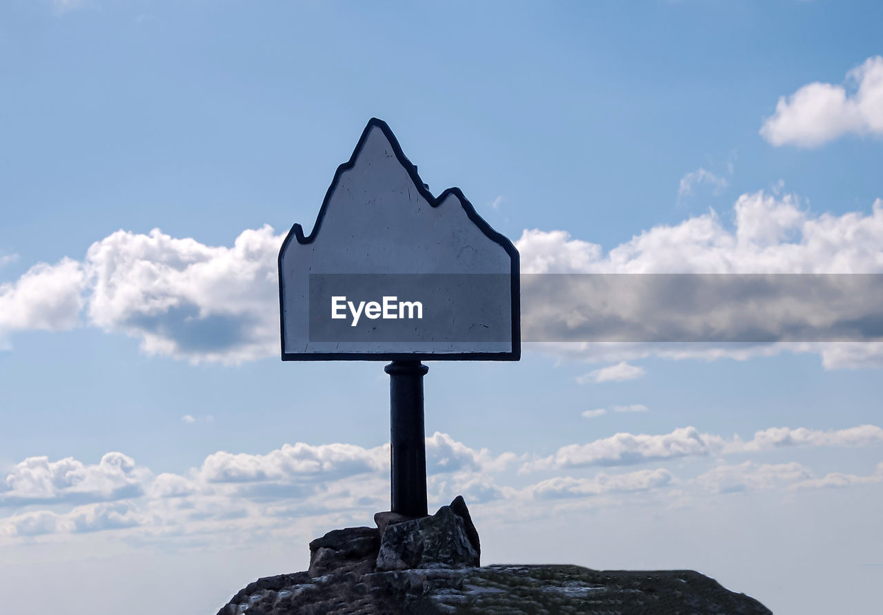 CLOSE-UP OF SIGN ON ROCK AGAINST SKY