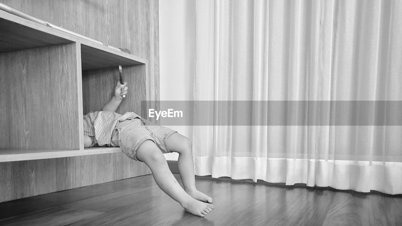 Low section of boy lying in shelf