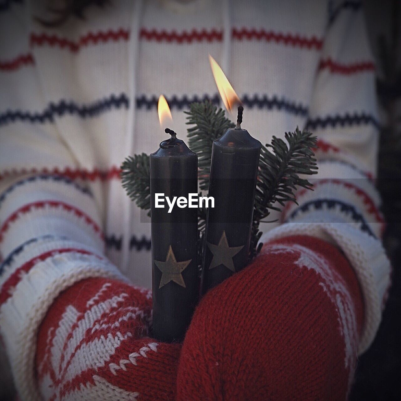 Midsection of child holding lit candles during winter