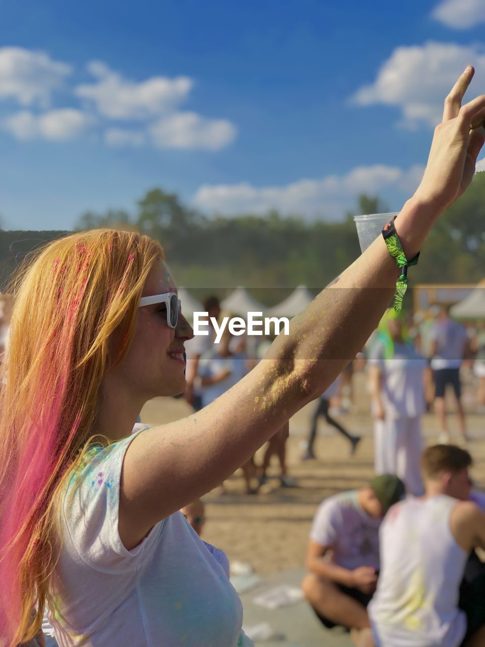 Young woman wearing sunglasses with arm raised in music festival