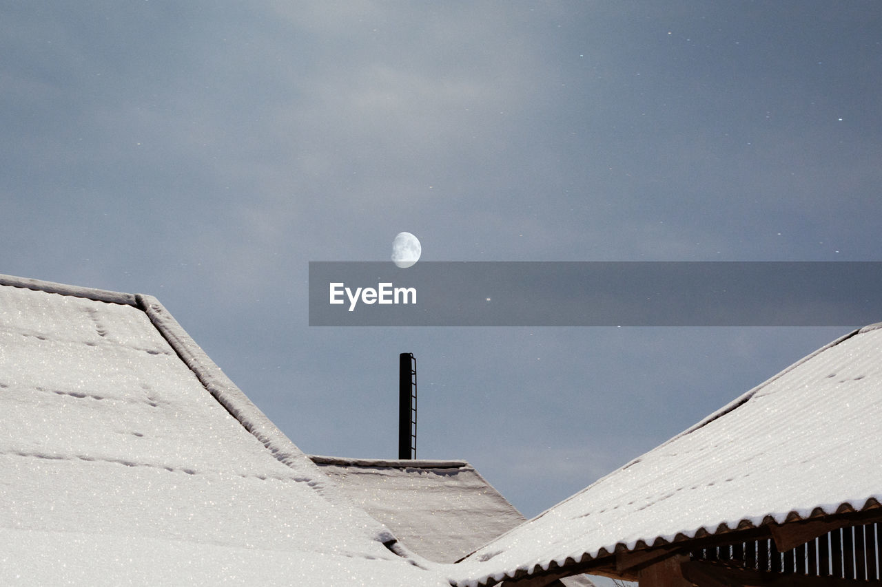 Low angle view of snow covered roof against sky