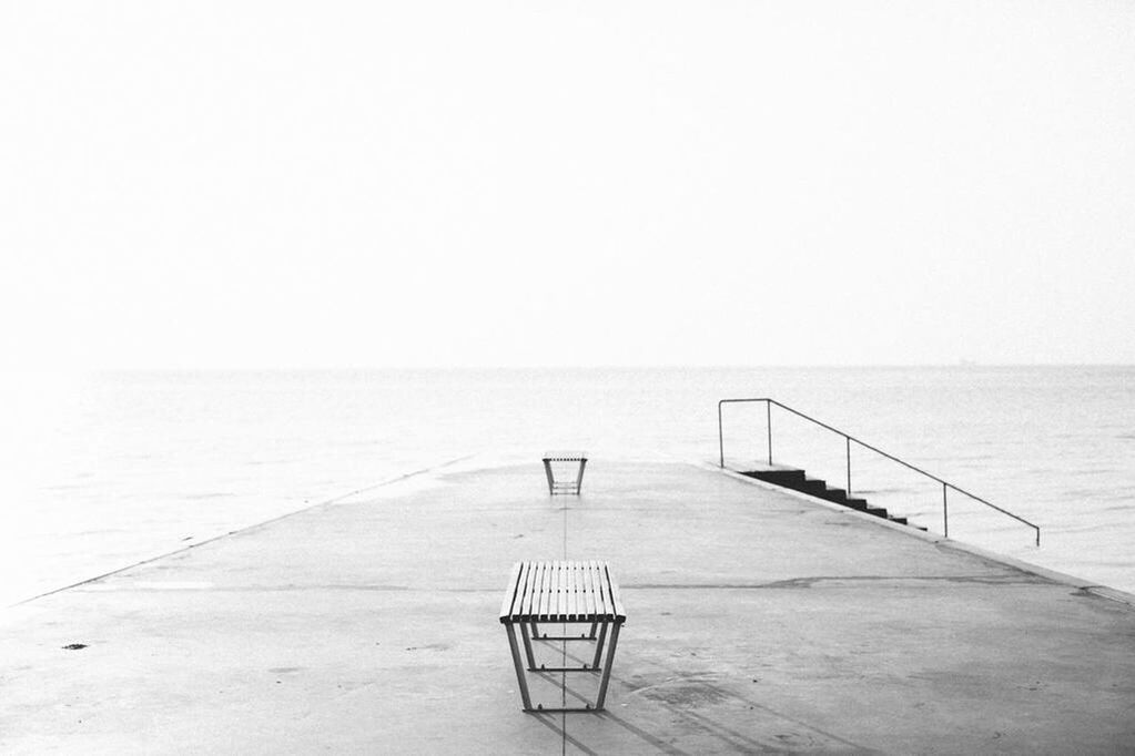 Empty benches on jetty against the sea