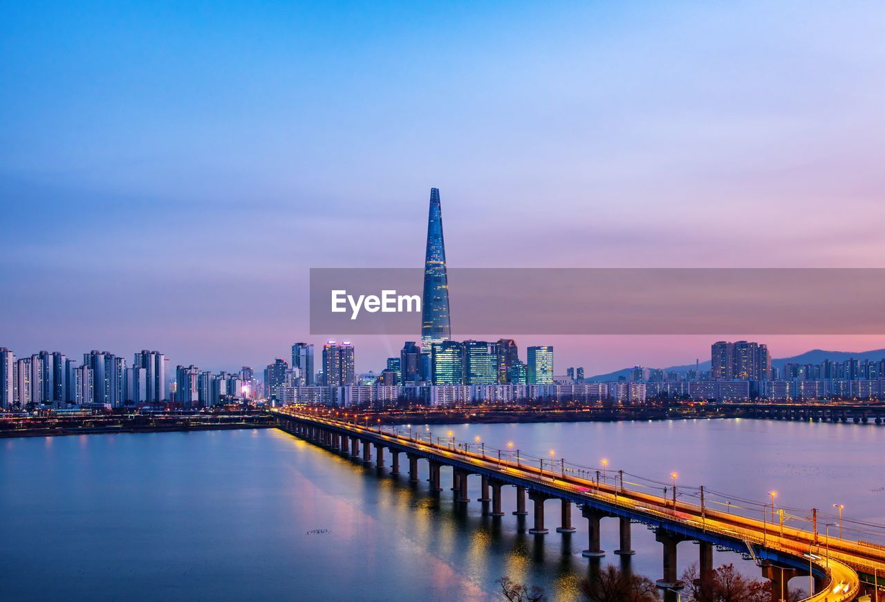 ILLUMINATED MODERN BUILDINGS IN BAY AGAINST SKY