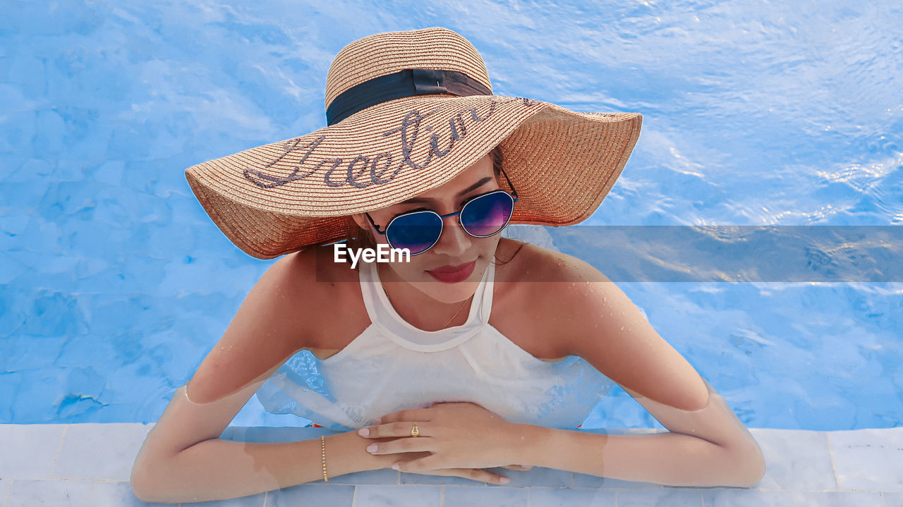 High angle view of woman wearing sunglasses and hat in swimming pool