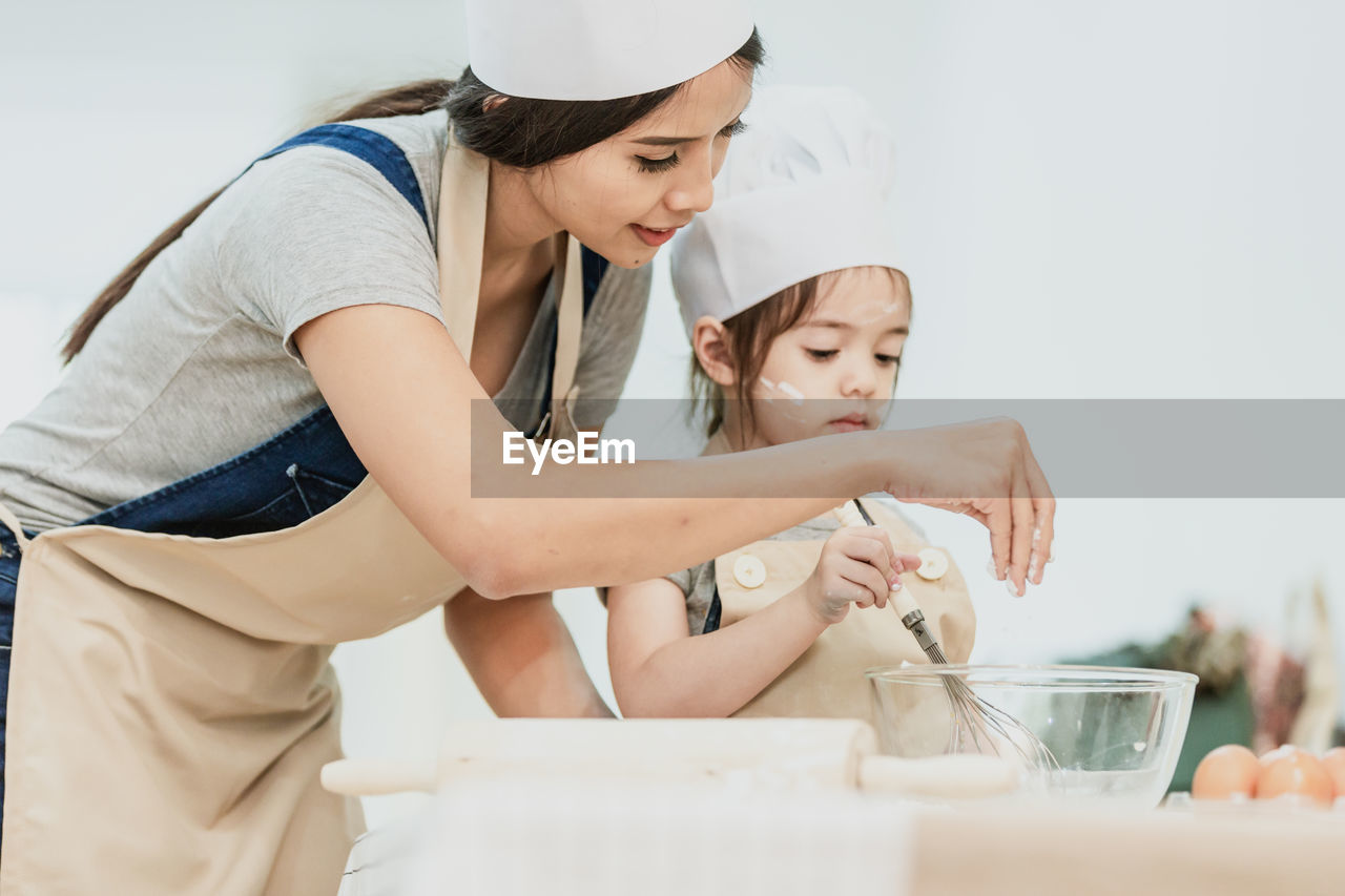 Mother and daughter preparing food on table