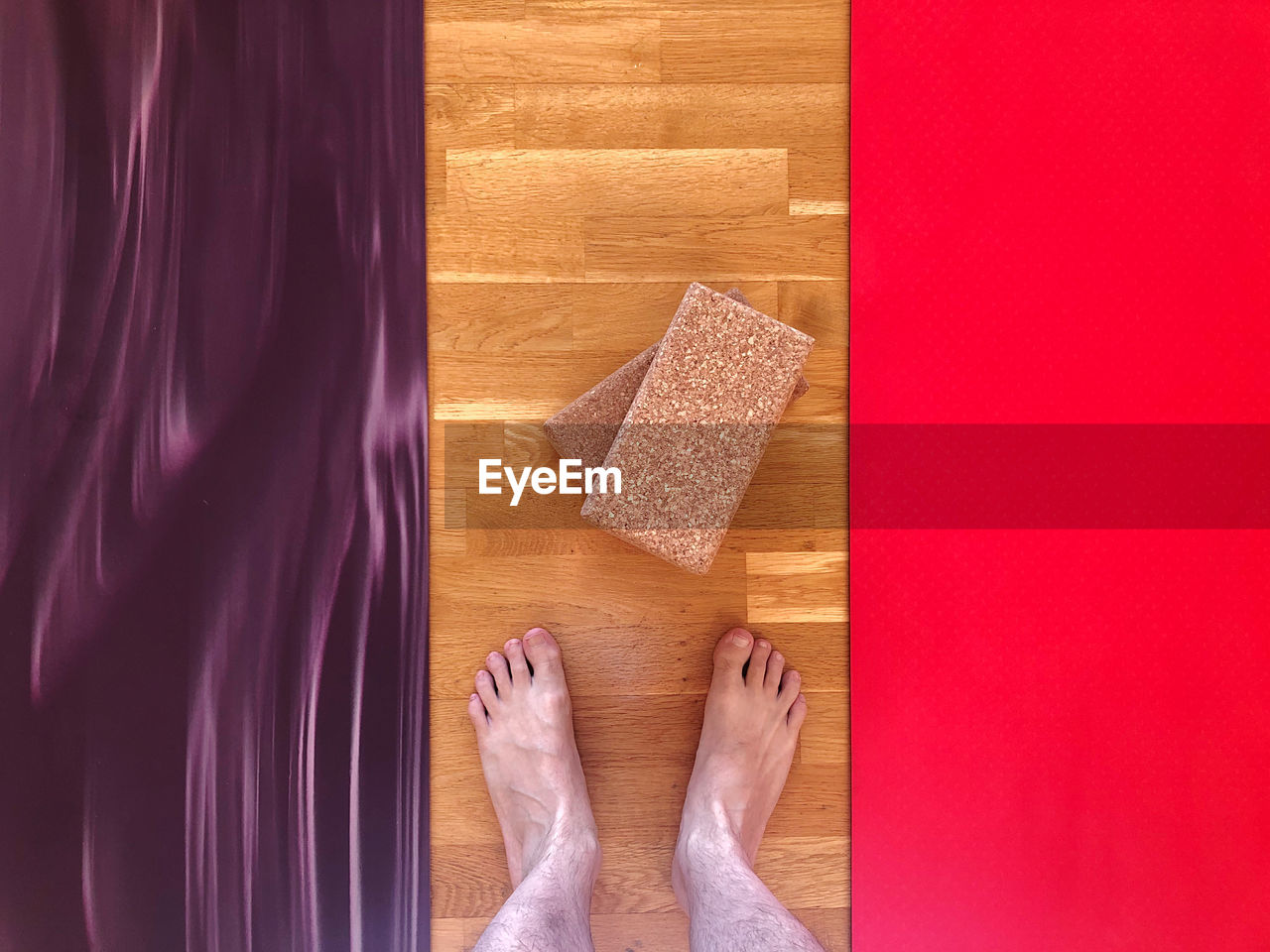 LOW SECTION OF PERSON RELAXING ON WOODEN FLOOR