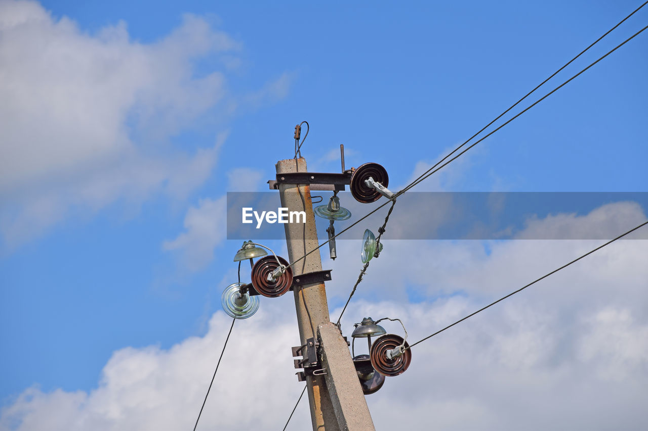 Low angle view of electricity pole against cloudy sky