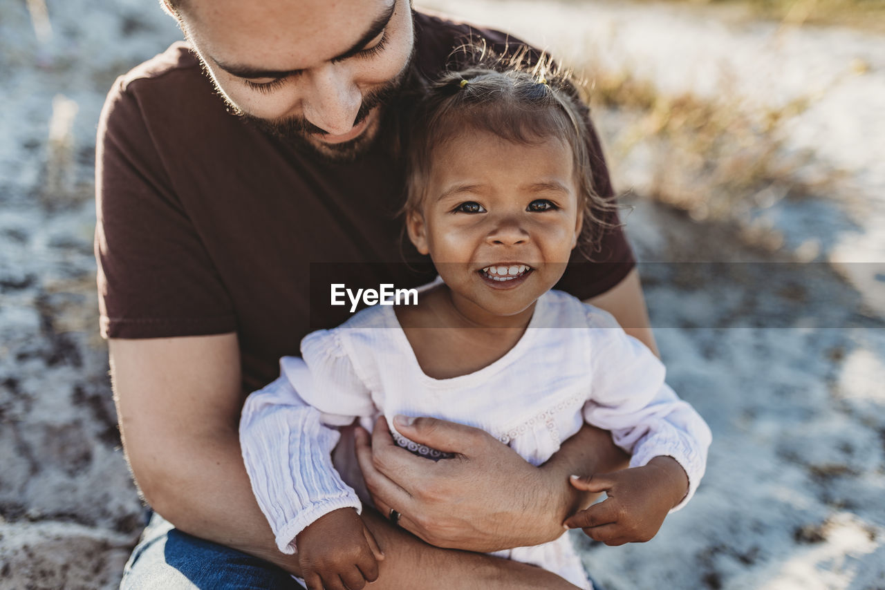 Close up of father holding young toddler girl at beach